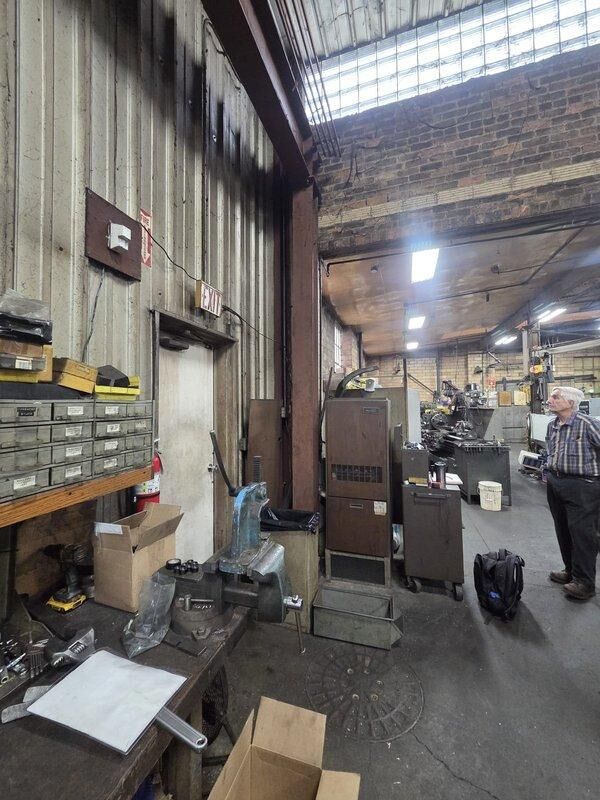 Conducted mini-split system estimate at industrial machine shop facility. Inspected existing HVAC infrastructure including ductwork, vertical piping, and current heating unit. Evaluated space requirements and structural considerations for new mini-split installation in workshop environment with metal corrugated walls, brick surfaces, and industrial equipment.