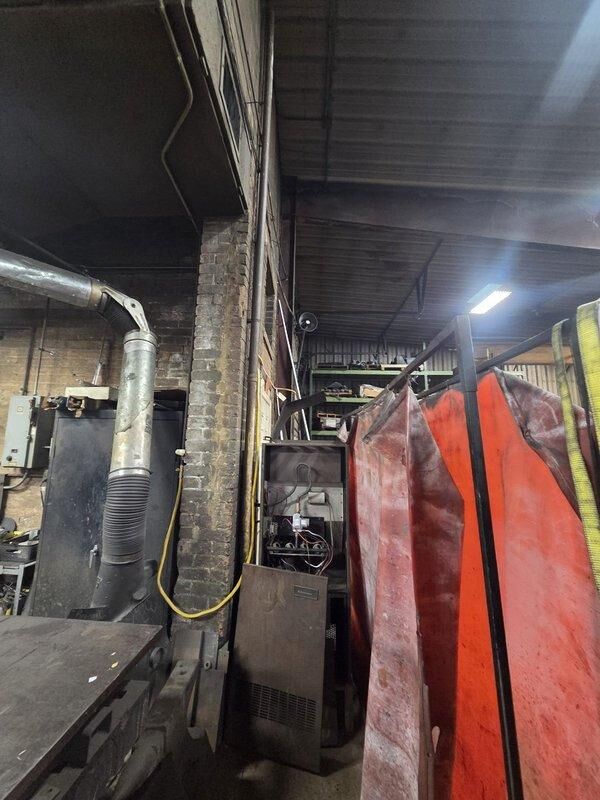 Conducted mini-split system estimate at industrial machine shop facility. Inspected existing HVAC infrastructure including ductwork, vertical piping, and current heating unit. Evaluated space requirements and structural considerations for new mini-split installation in workshop environment with metal corrugated walls, brick surfaces, and industrial equipment.