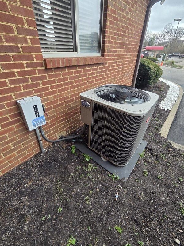 Conducted commercial AC replacement estimate for a rooftop unit at Extended Stay property. Inspected existing outdoor condenser unit mounted on concrete pad with adjacent electrical disconnect box, noting significant debris accumulation around flexible conduit/drain pipes requiring maintenance. Documented current system condition with photos to provide accurate replacement options suitable for the commercial application.