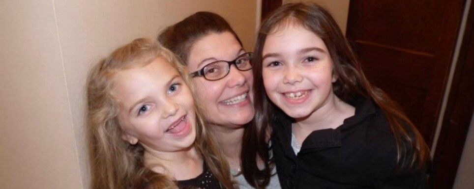 Rob's wife smiling with their two young daughters