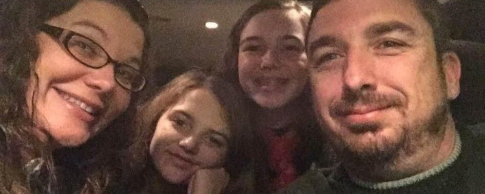 Rob smiling for a picture with his wife and two young daughters