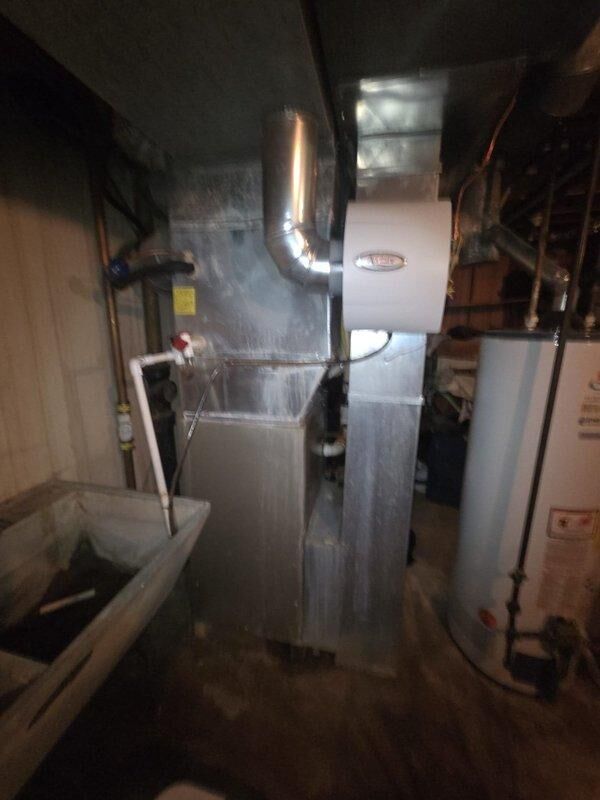 Conducted comprehensive evaluation of existing HVAC system, including inspection of digital thermostat and basement equipment configuration. Assessment focused on furnace unit with attached cylindrical humidifier, associated ductwork, and integration with current water heating system to prepare replacement estimate.